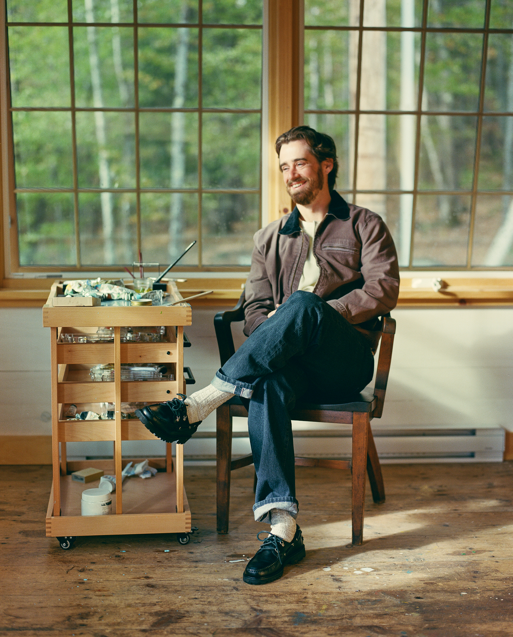 Stevie sitting in a studio chair near painting supplies